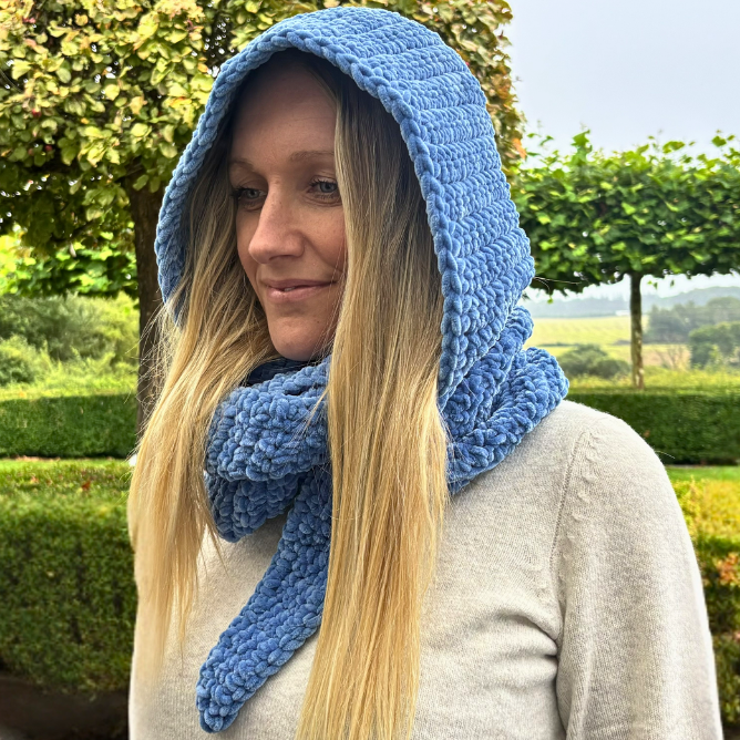 Kvinde iført blåt Sophie Hood hæklet halstørklæde med hætte i blå Honey Bunny garn fra Hobbiigarn, vist forfra.